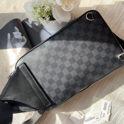 Black checkered patterned bag on a light wooden surface with a small plant in the background.