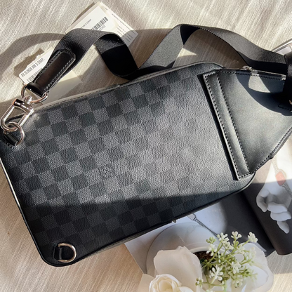 Black checkered patterned bag on a light wooden surface with flowers and a magazine.