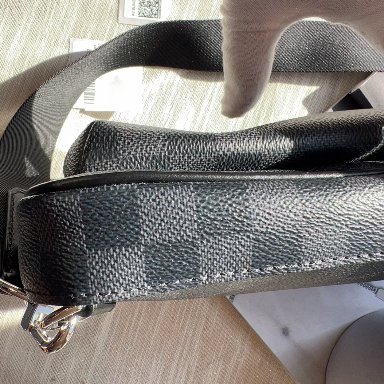 Close-up of a black leather handbag with a textured pattern on a light surface.