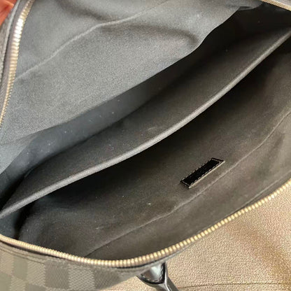 Close-up of the interior of a gray checkered bag with a hand holding the zipper open, showing a dark gray fabric lining and a small black rectangular tag inside.