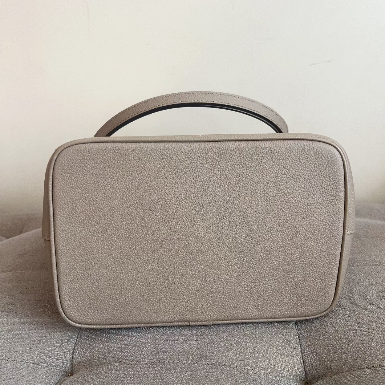 Beige handbag on a gray sofa against a light background