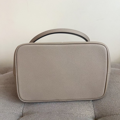 Beige handbag on a gray sofa against a light background