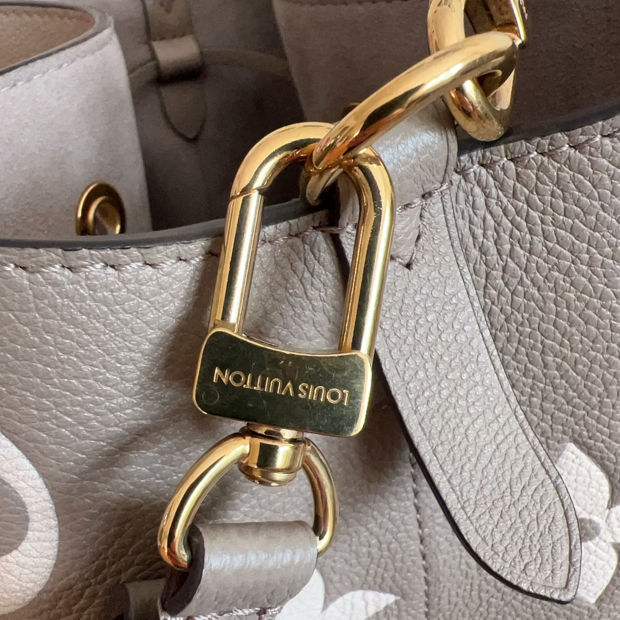 Close-up of a Louis Vuitton handbag with a gold padlock.