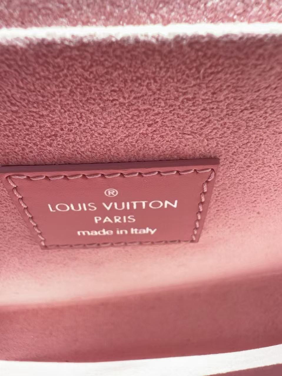 Close-up of a Louis Vuitton label on a pink textured surface
