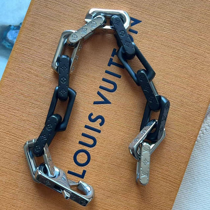 A Louis Vuitton chain bracelet with black and silver links, displayed on top of its brown Louis Vuitton box.