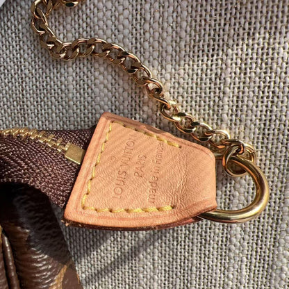 Close-up of a Louis Vuitton bag tag with chain on a textured surface