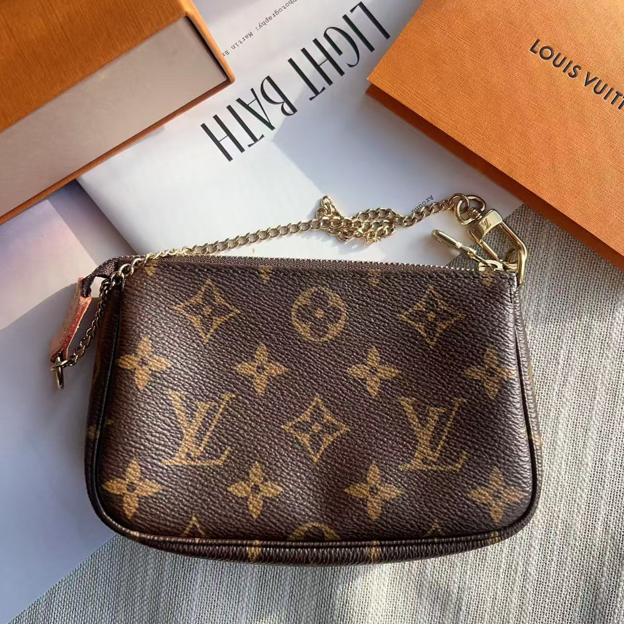 Louis Vuitton monogram handbag with a chain strap on a light surface with a Louis Vuitton box in the background.