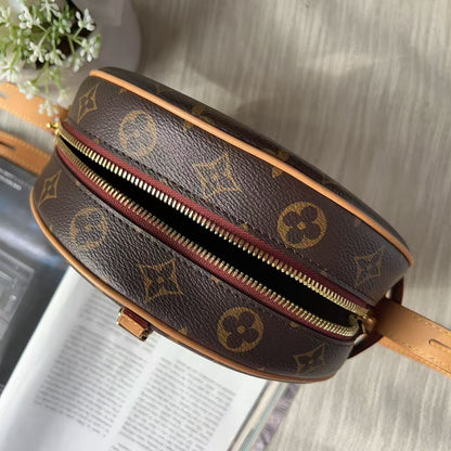 A Louis Vuitton monogram canvas round crossbody bag with a gold-tone zipper, shown in a styled flat-lay setting with a magazine and white flowers in the background.