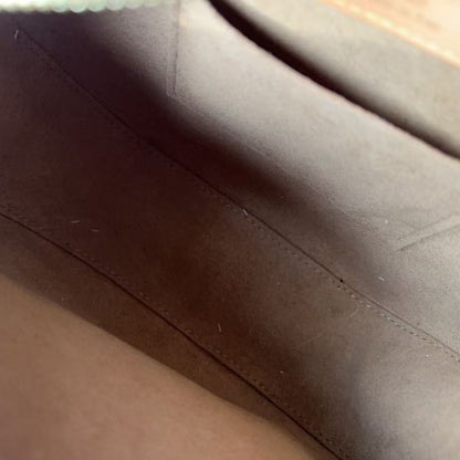 Close-up of a brown suede or suede-like fabric interior with visible stitching and a small portion of a tan leather patch at the top.