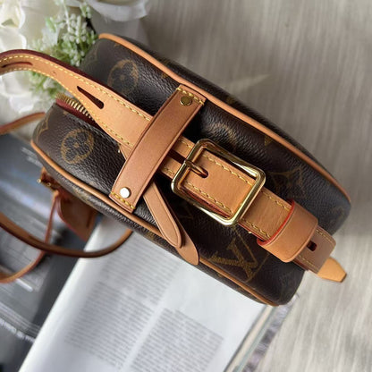 A Louis Vuitton monogram canvas round shoulder bag with tan leather trim and a gold-tone buckle, shown resting on an open magazine over a light gray surface.