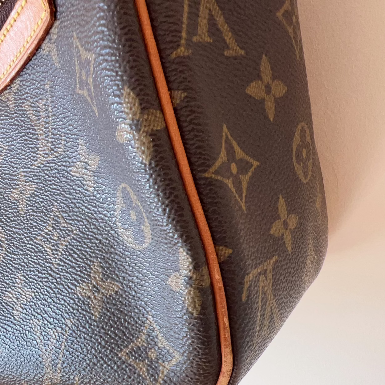 Close-up of a brown handbag with monogram pattern on a white background