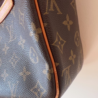 Close-up of a brown handbag with monogram pattern on a white background