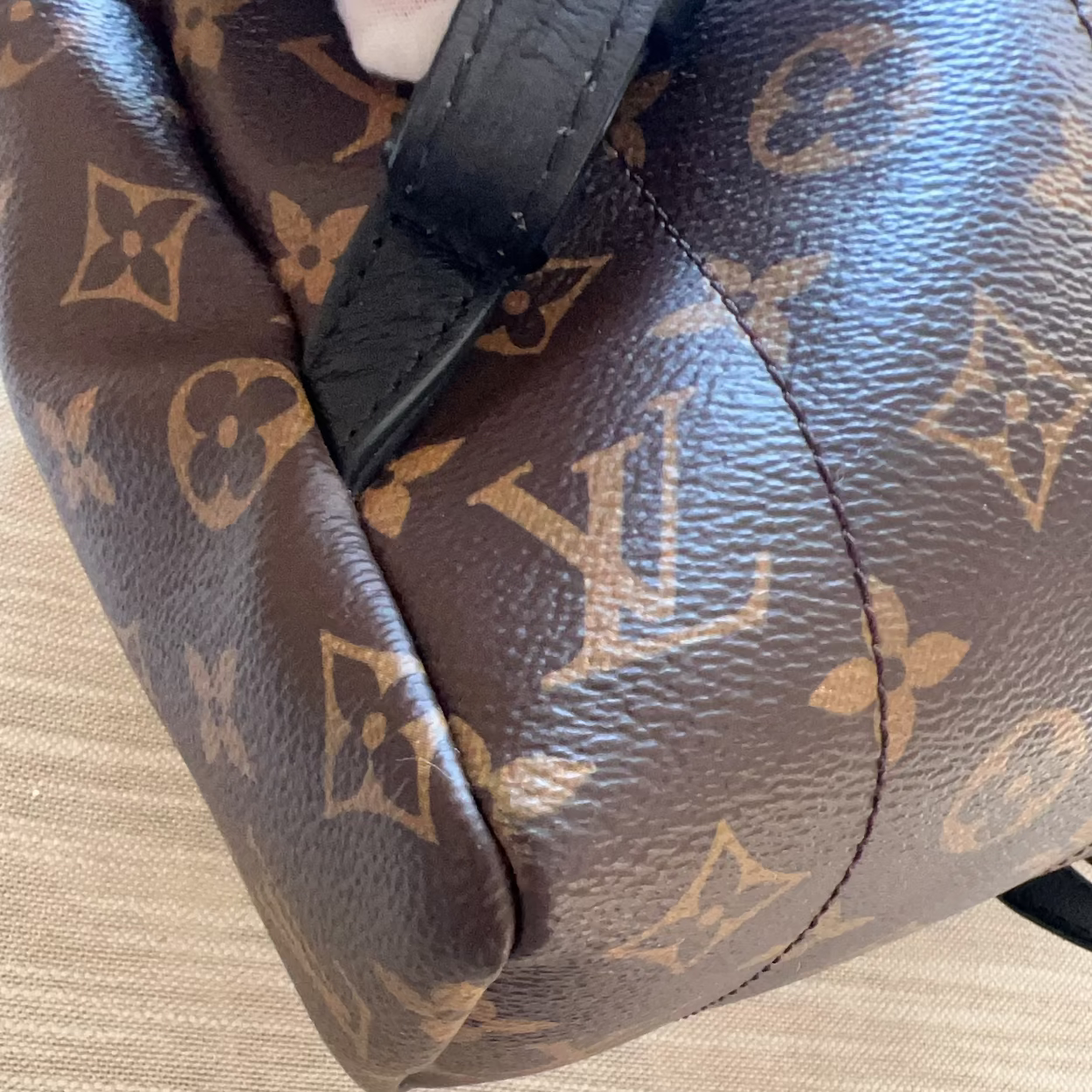 Brown leather bag with monogram pattern on a beige surface
