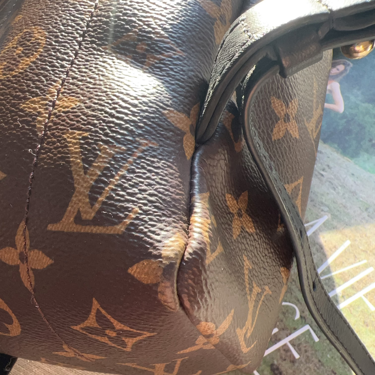 Close-up of a brown leather handbag with a pattern, on a reflective surface.