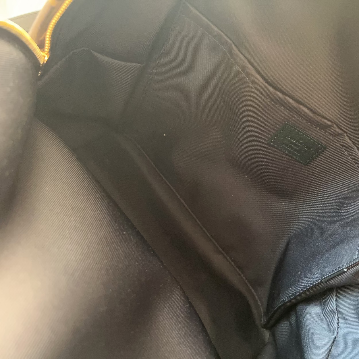Close-up of a black fabric patch on a gray garment with a visible brand logo.