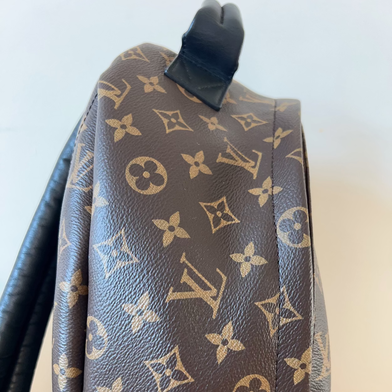 Brown backpack with monogram pattern on a light background