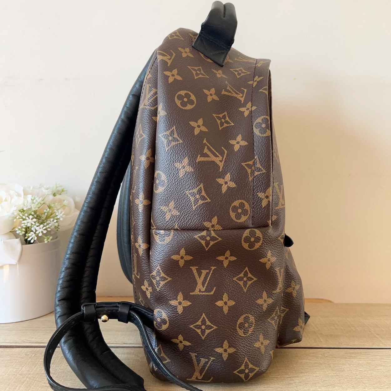 Brown backpack with monogram pattern on a wooden surface