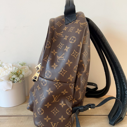 Brown backpack with monogram pattern on a light wooden surface