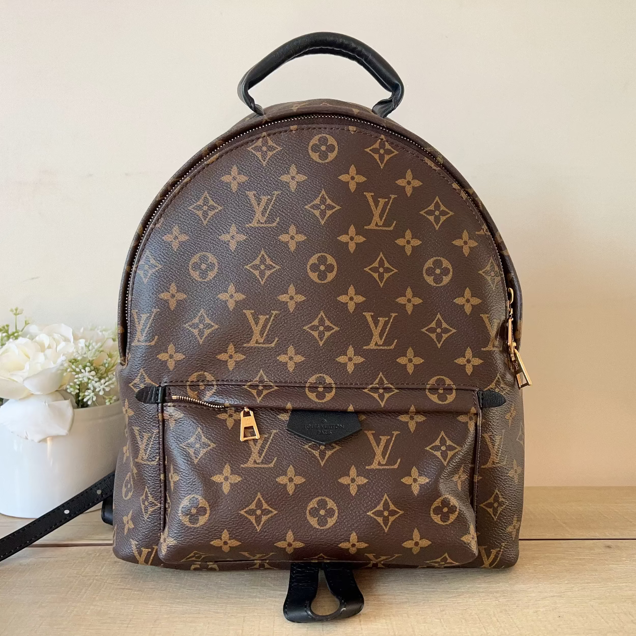 Brown backpack with monogram pattern on a wooden surface with a light background