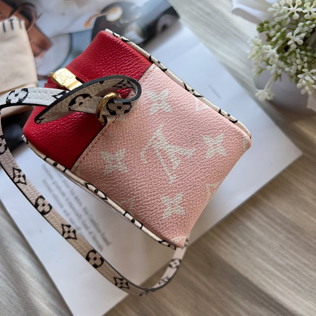 Pink wallet with monogram design on a surface with a blurred background