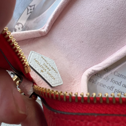 Close-up of a red handbag with gold zipper and visible brand label.