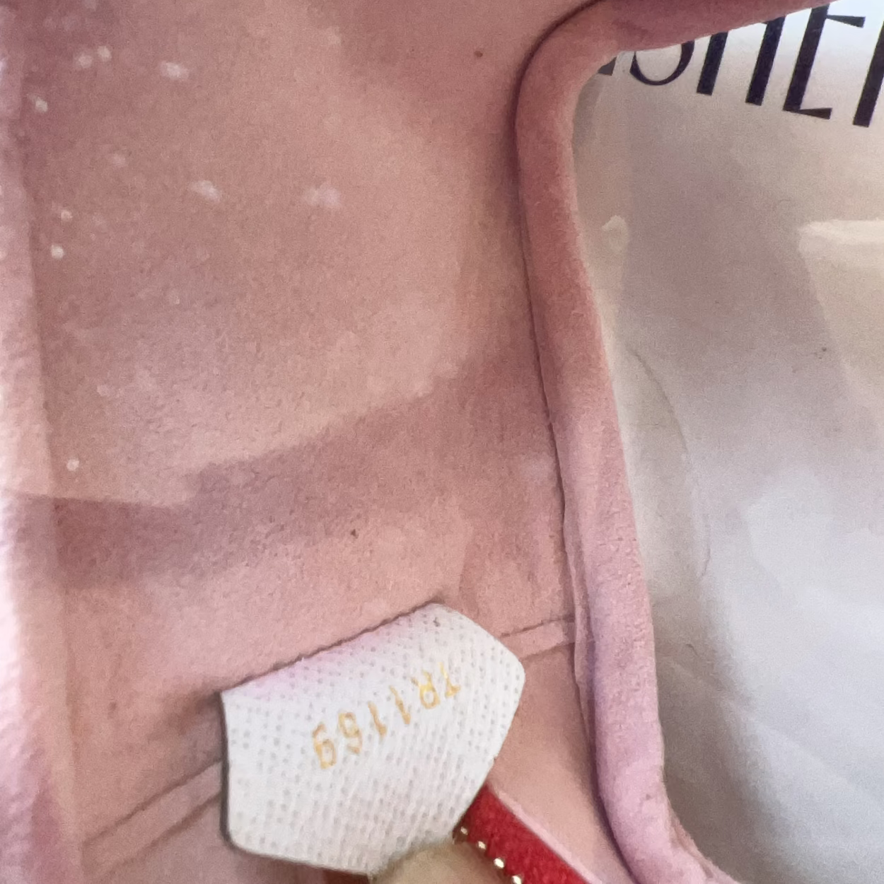 Close-up of a pink garment with a label inside, showing brand details.