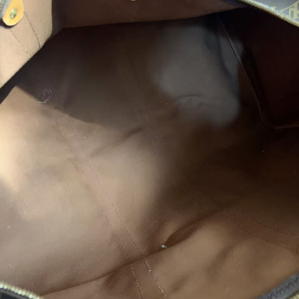 Close-up view of the interior of a Louis Vuitton bag, showing the brown fabric lining, gold-tone hardware, and a portion of the classic monogram canvas at the top.