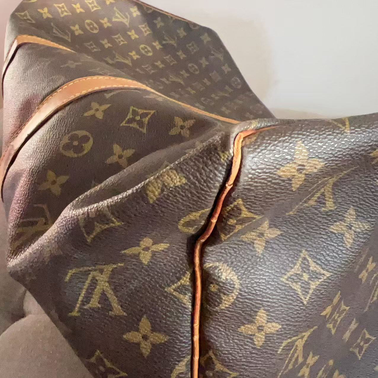 Close-up of a Louis Vuitton monogram canvas bag in dark brown with tan leather trim and gold-tone monogram print.