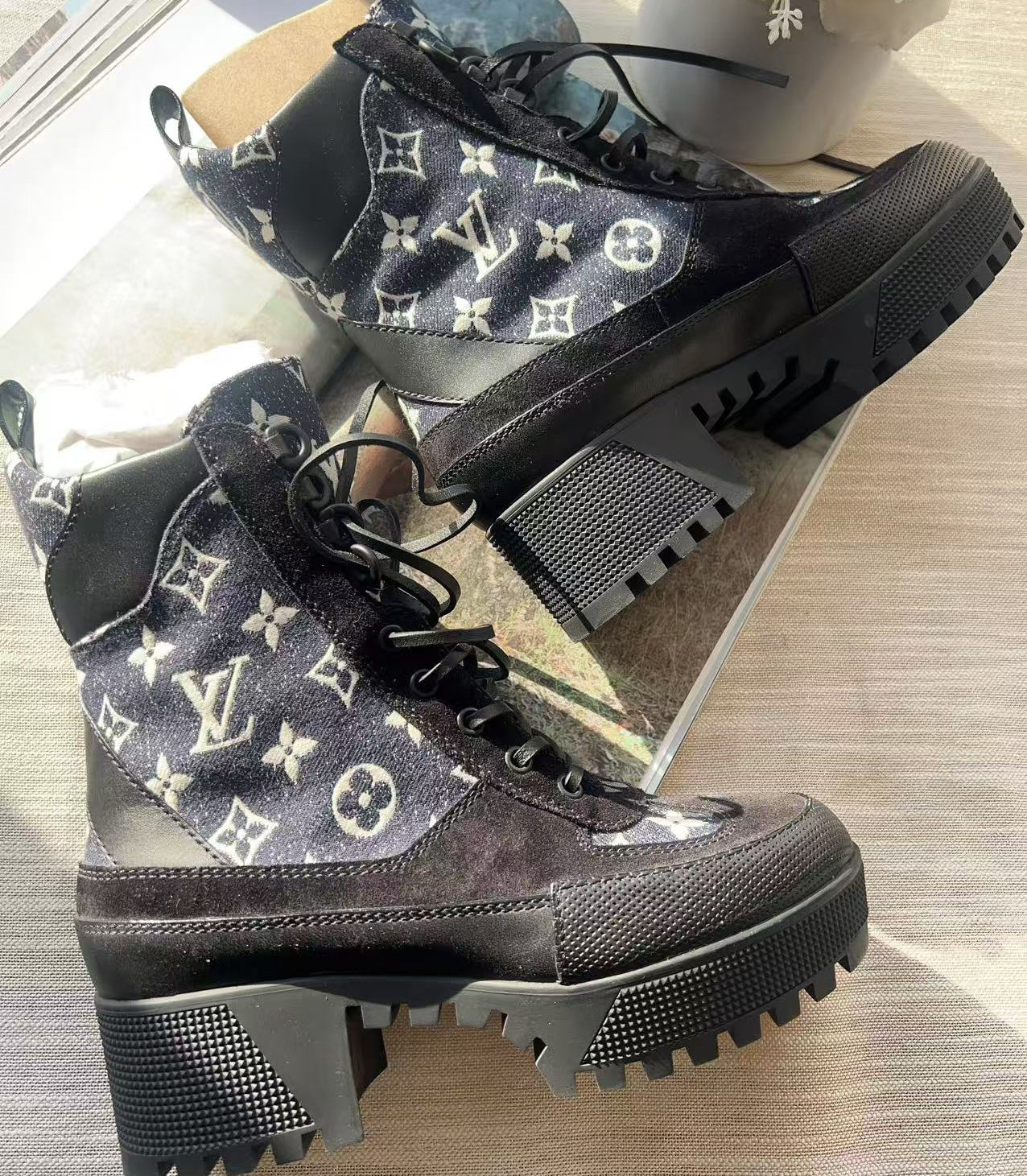 Black boots with patterned design on a reflective surface