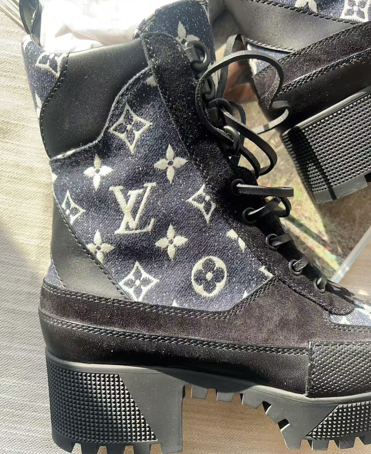 Black and white patterned boots with brand logo on a reflective surface