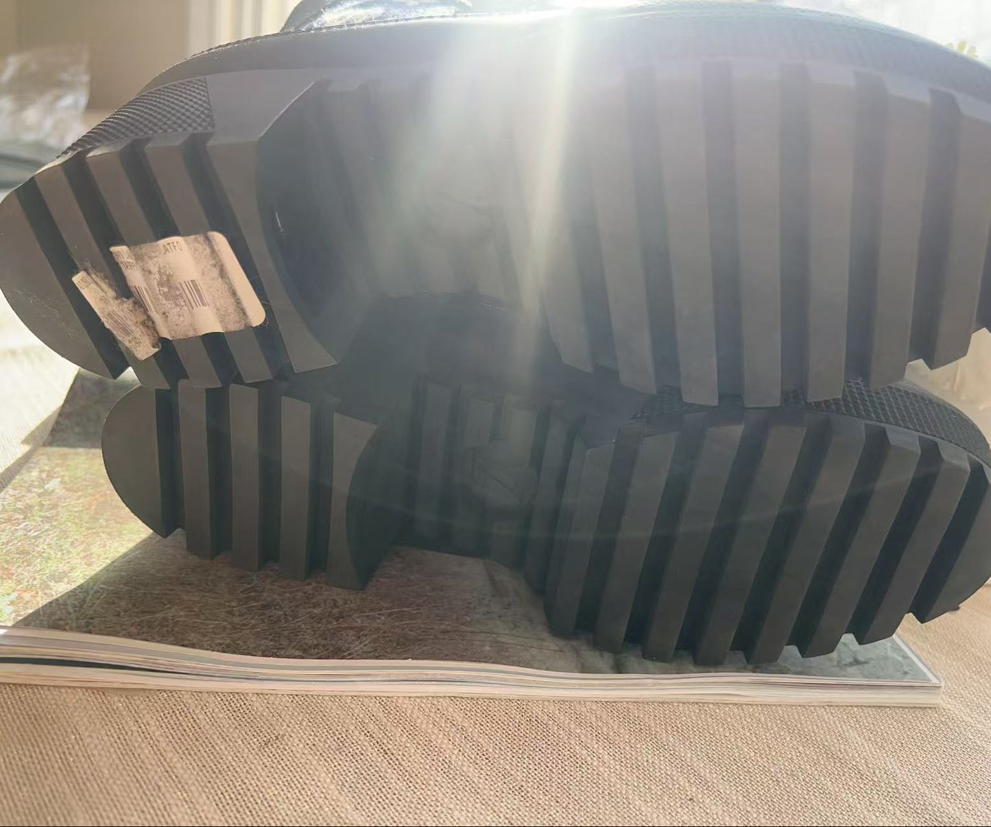 Close-up of a black rubber sole with tread pattern on a light wooden floor.