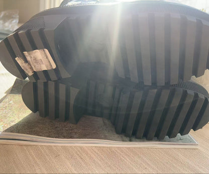 Close-up of a black rubber sole with tread pattern on a light wooden floor.