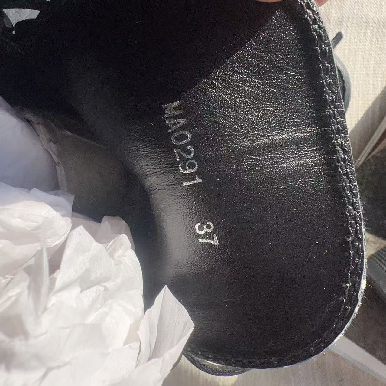 Black shoe with visible size and brand details on a white surface