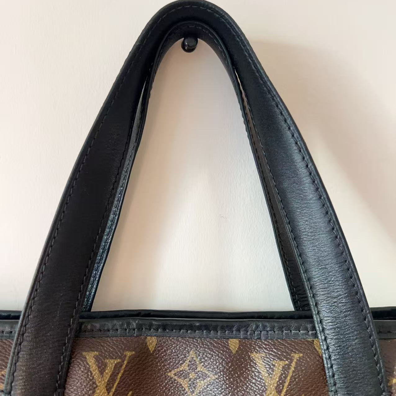 Close-up of a Louis Vuitton handbag with monogram pattern and black handle.