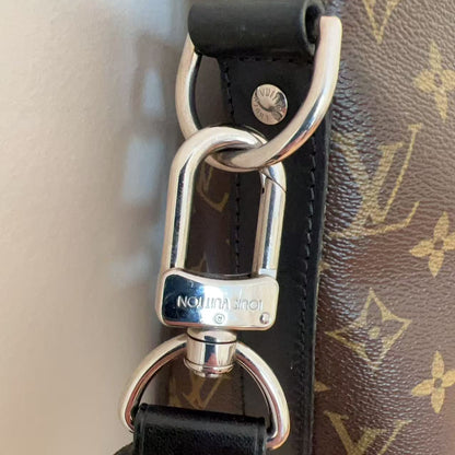 Close-up of a black leather strap with a silver clasp on a Louis Vuitton bag.