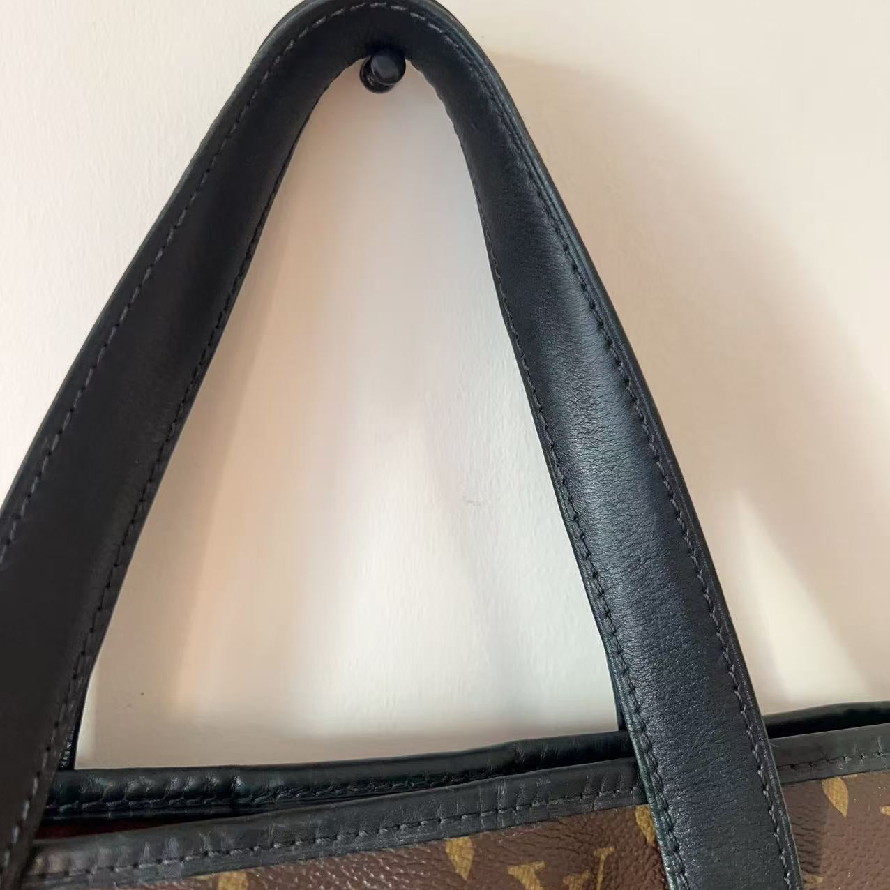 Close-up of a brown leather handbag with a visible brand logo on a white background