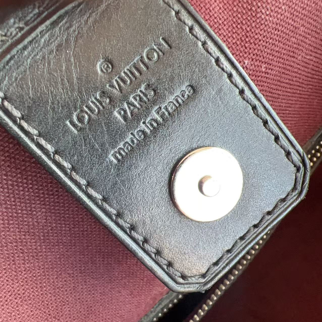 Louis Vuitton leather tag with brand name and 'Made in France' text on a maroon background.