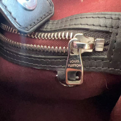 Close-up of a Louis Vuitton zipper on a red leather bag.
