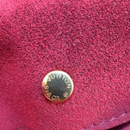 Close-up of a red textured surface with a gold Louis Vuitton button.