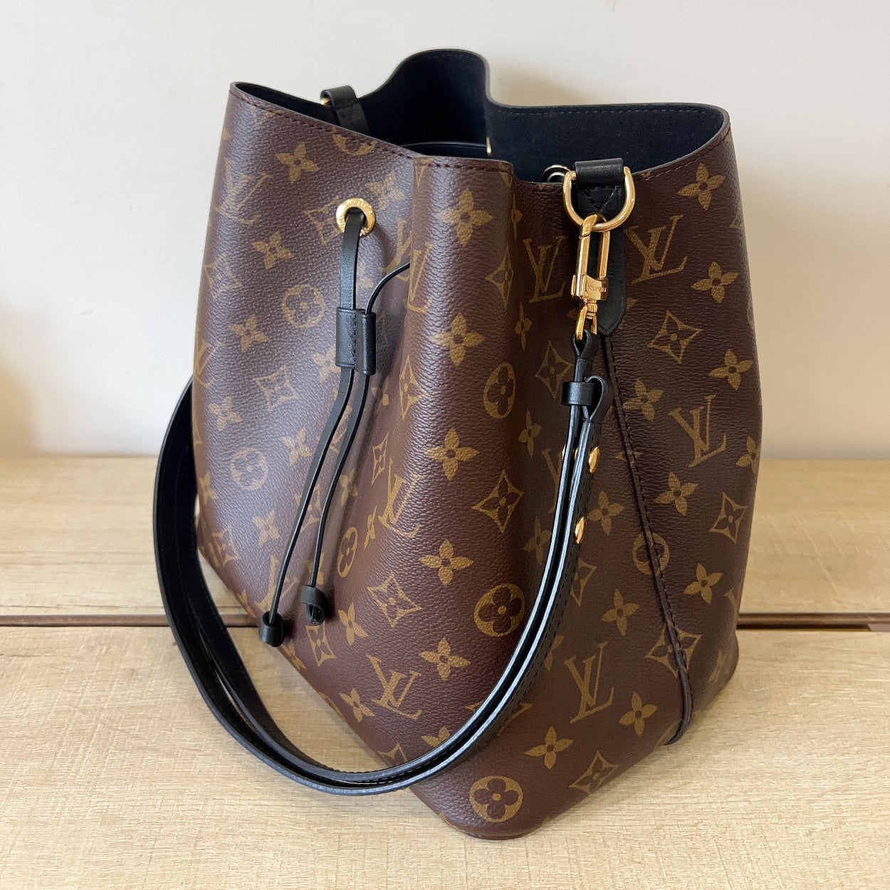 Designer handbag with monogram pattern on a wooden surface