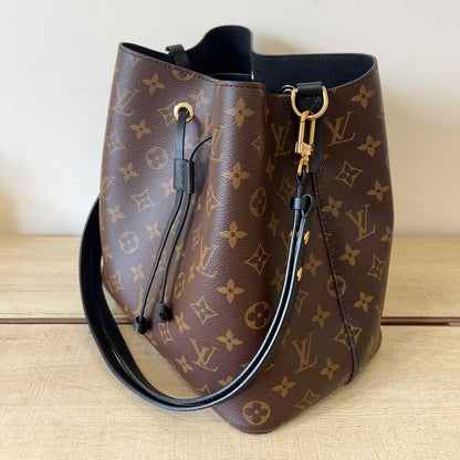 Designer handbag with monogram pattern on a wooden surface