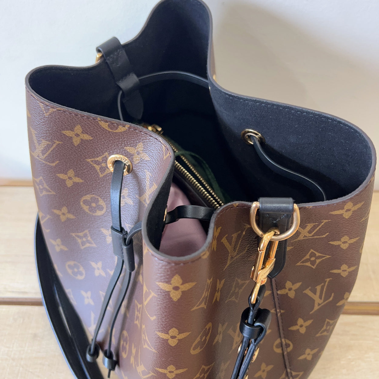 Designer handbag with monogram pattern on a light wooden surface