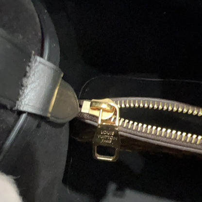 Close-up of a gold zipper on a black bag with 'Louis Vuitton' branding.