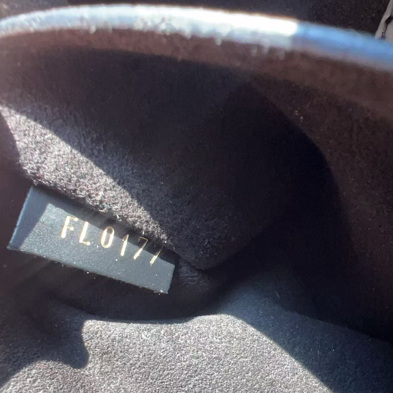 Close-up of a dark gray textured fabric interior with a small black label printed with the code 'FL0177' in light gray.