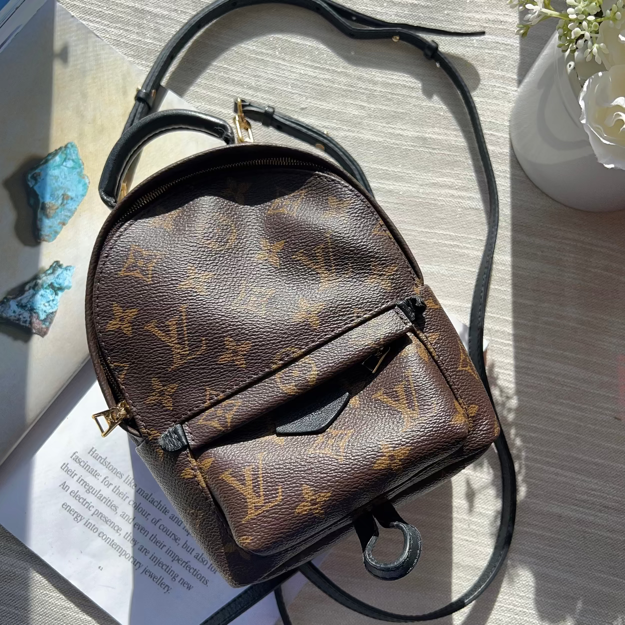Brown leather backpack with monogram pattern on a wooden surface