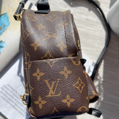 Brown leather handbag with monogram pattern on a light wooden surface