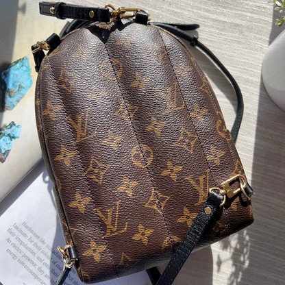Brown monogram handbag with black drawstring on a light gray surface.