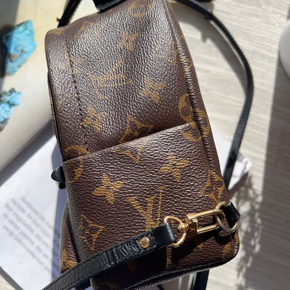 Brown leather handbag with gold monogram pattern on a light surface