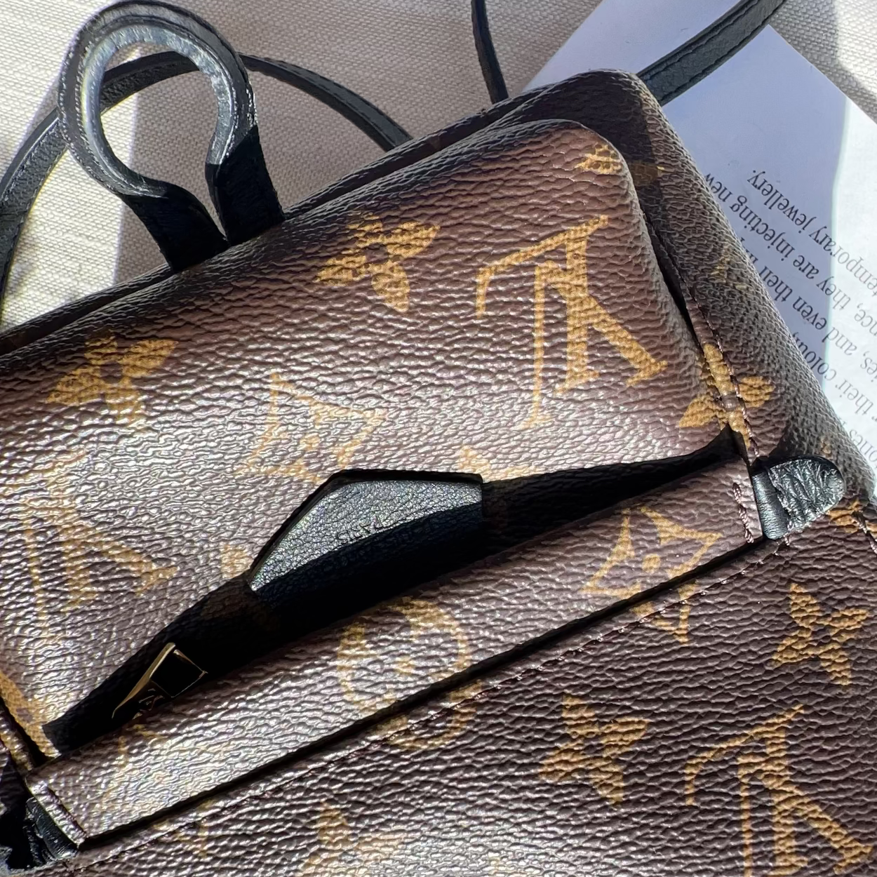 Brown leather handbag with gold logo pattern on a light background