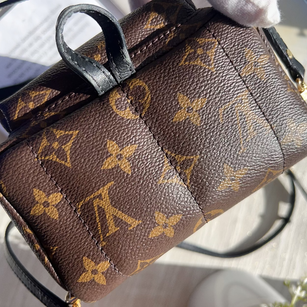 Brown handbag with monogram pattern on a light wooden surface